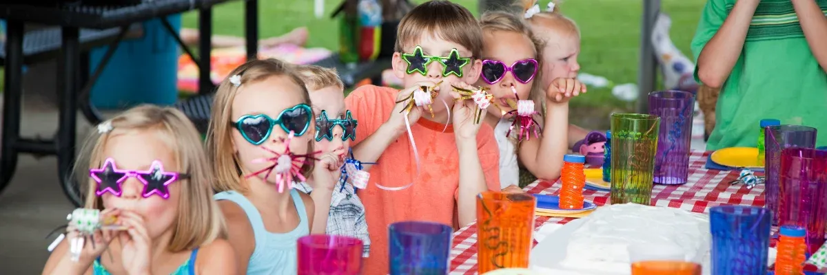 Kids in novelty sunglasses at an outdoor birthday party table in Springfield